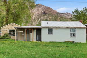 View of front of home with a mountain view, a front lawn, concrete block siding, and a metal roof