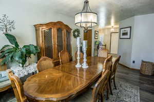 Dining area featuring dark wood-style flooring, shows view to formal entry