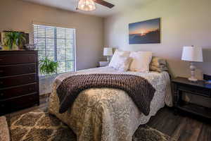 Bedroom #2 featuring dark wood-style floors & a ceiling fan. Room overlooks front courtyard & pond. Oh the sound!