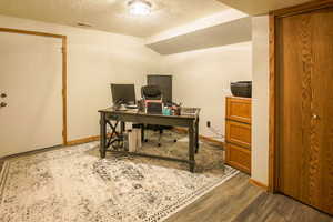 Office area with closet and wood finished floors and entry door to back yard. There are two downstairs exits.