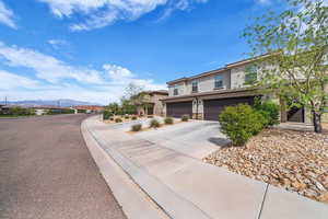 View of front of property featuring driveway, a mountain view, stucco siding, a garage, and stone siding