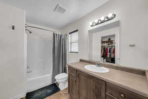 Bathroom featuring vanity, shower / tub combo, and a walk in closet