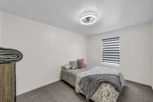 Bedroom featuring dark carpet and a textured ceiling