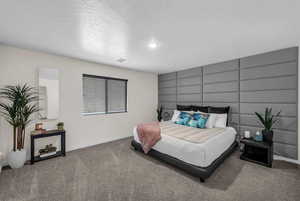 Bedroom with an accent wall, carpet floors, and a textured ceiling