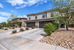 Traditional-style house with stucco siding, a garage, driveway, and stone siding