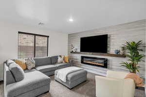Carpeted living area with an accent wall and a glass covered fireplace