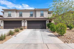 View of front of property with stone siding, stucco siding, an attached garage, and driveway
