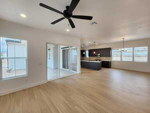 Unfurnished living room with light wood-style flooring, ceiling fan, and a chandelier