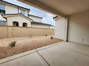 Partially fenced backyard featuring a patio