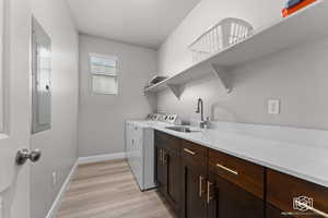 Laundry area with cabinet space, washing machine and dryer, light wood-style floors, and electric panel