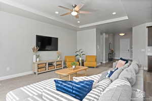 Living area featuring a raised ceiling, a ceiling fan, and recessed lighting