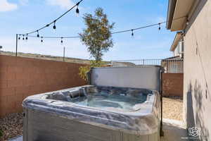 Fenced backyard featuring a hot tub