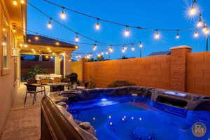 View of pool with a fenced backyard, patio surround, a hot tub, and an outdoor living space with a fire pit