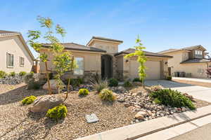 View of front facade featuring concrete driveway, an attached garage, stone siding, stucco siding, and a tiled roof