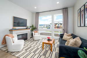Living room with a glass covered fireplace, wood finished floors, and recessed lighting