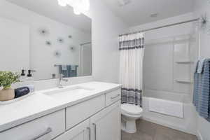 Bathroom with vanity, shower / bathtub combination with curtain, and light tile patterned flooring