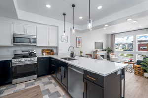 Kitchen featuring two tone cabinets, stainless steel appliances, a peninsula, light stone countertops, and a fireplace