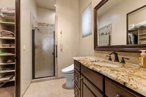 Full bathroom with a walk in closet, a stall shower, vanity, and light tile patterned floors