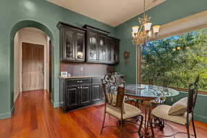 Dining area featuring dark wood-style floors, arched walkways, and hanging lights