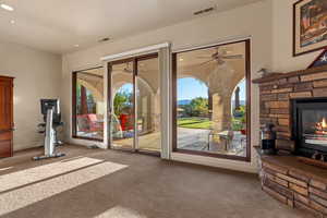 Entryway featuring carpet floors, a stone fireplace, plenty of natural light, ceiling fan, and recessed lighting