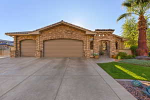 View of front facade with stone siding, a garage, a tiled roof, and concrete driveway