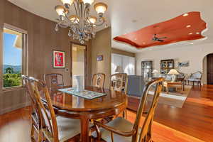 Dining room featuring hardwood / wood-style floors, a ceiling fan, arched walkways, a tray ceiling, and a chandelier