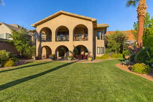 Rear view of house with a balcony, stucco siding, a yard, and a patio