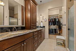 Bathroom featuring double vanity, a stall shower, a walk in closet, and light tile patterned floors