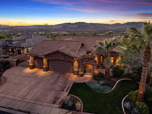 Mediterranean / spanish home with stone siding, an attached garage, a tile roof, concrete driveway, and a mountain view
