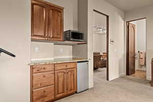 Kitchen with light stone counters, wood finish cabinets, light carpet, and stainless steel appliances