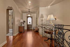 Foyer with arched walkways, dark wood-style floors, and recessed lighting