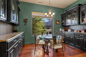 Dining space featuring dark wood-style flooring and a chandelier