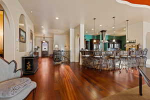 Dining area with arched walkways, dark wood-style floors, and recessed lighting