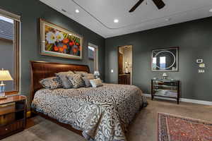 Bedroom with ensuite bathroom, dark colored carpet, recessed lighting, and ceiling fan