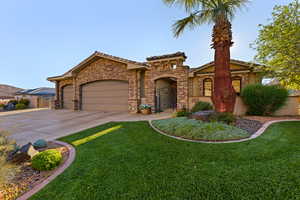 Mediterranean / spanish-style home with a front lawn, an attached garage, concrete driveway, a tile roof, and stone siding
