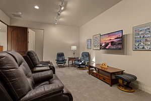 Carpeted living area with rail lighting and baseboards
