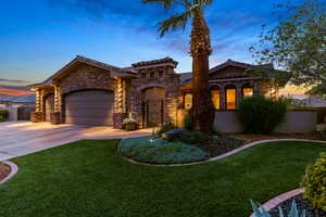 Mediterranean / spanish-style home featuring concrete driveway, stone siding, an attached garage, and a lawn
