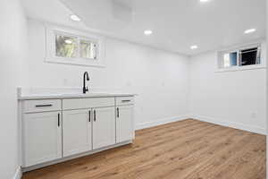 Bar featuring light wood finished floors, plenty of natural light, light stone countertops, and recessed lighting