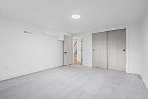 Unfurnished bedroom featuring light carpet and a closet
