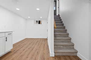 Stairway with wood finished floors and recessed lighting