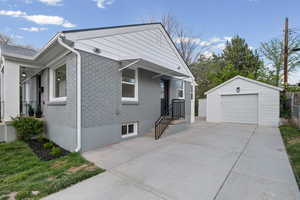 View of front of home featuring brick siding, a garage, an outdoor structure, and driveway