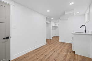 Bar area with light wood finished floors, recessed lighting, white cabinets, and light stone countertops