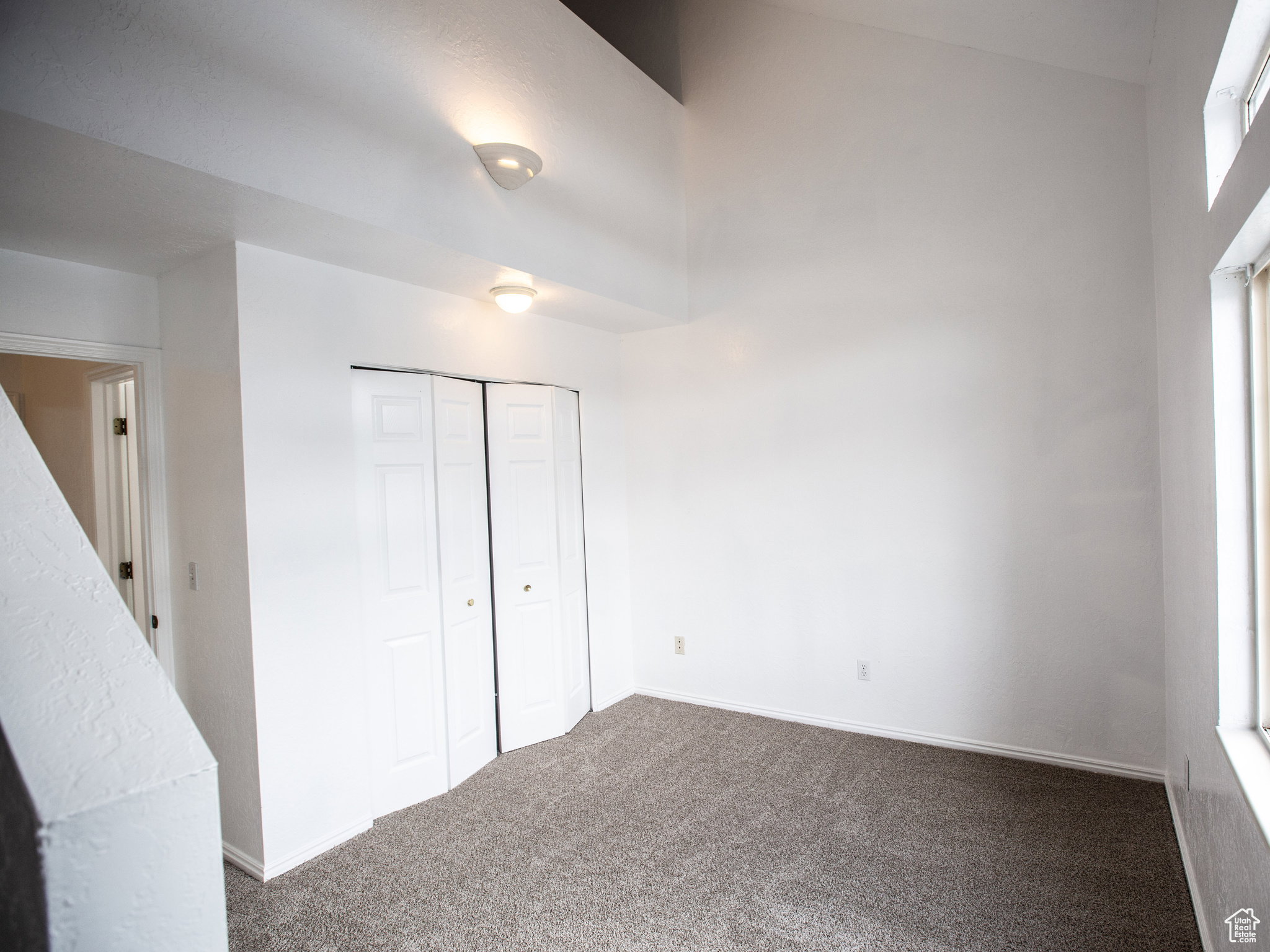 Unfurnished bedroom with dark carpet, a closet, and a high ceiling