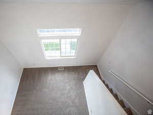 Unfurnished room featuring carpet flooring, a skylight, and lofted ceiling