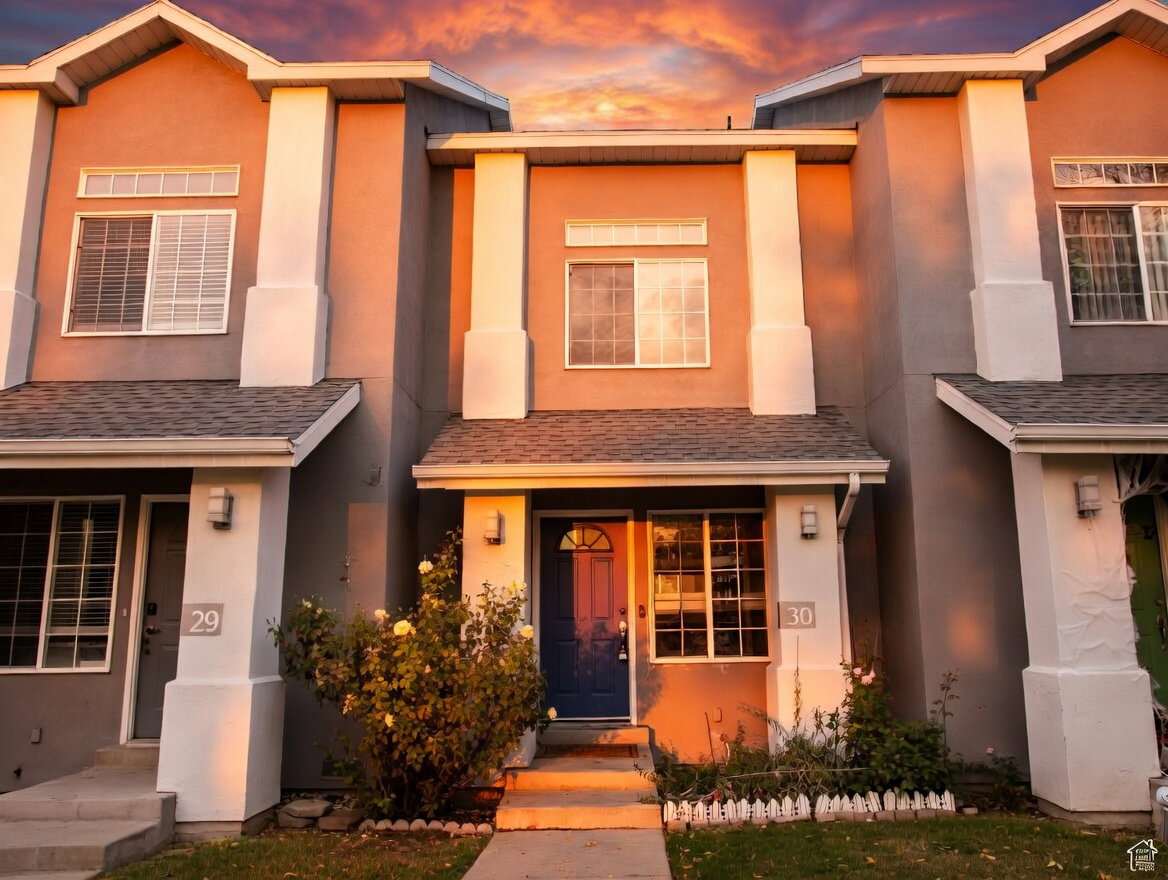 View of front of home with stucco siding and roof with shingles