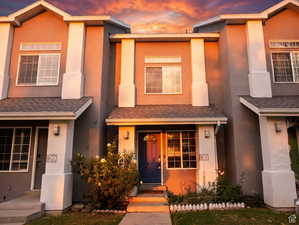 View of front of home with stucco siding and roof with shingles
