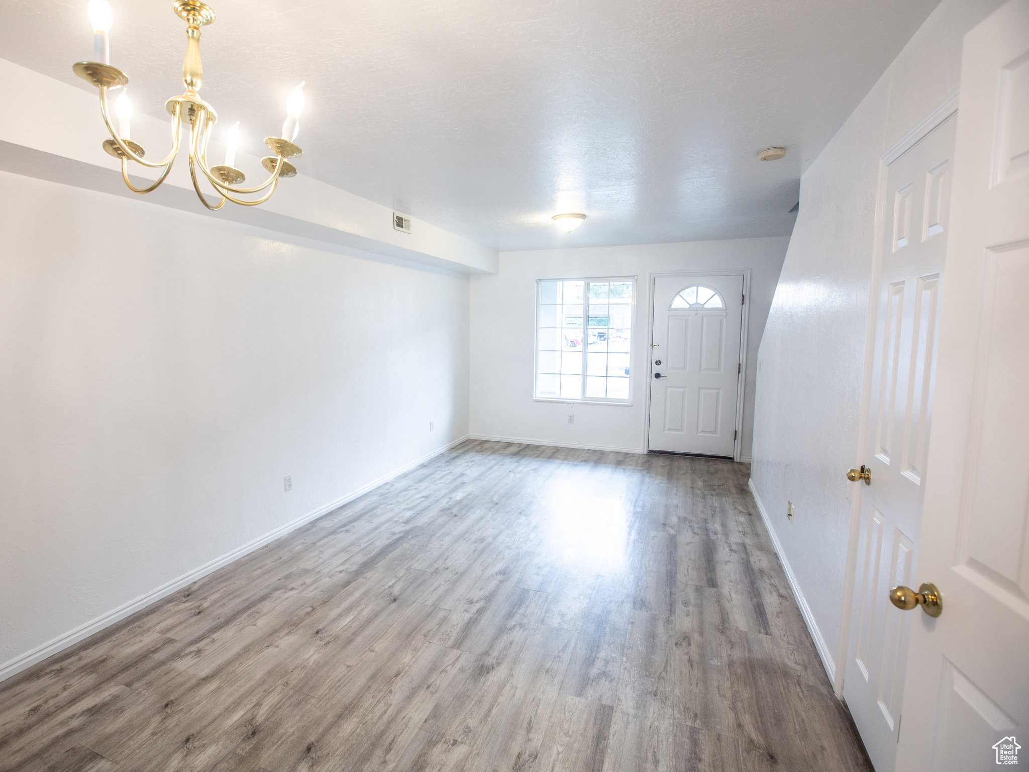 Entryway with wood finished floors and hanging lights