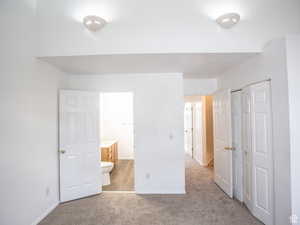 Unfurnished bedroom with light colored carpet, a closet, and ensuite bathroom