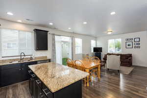 Kitchen featuring dark cabinets, open floor plan, light stone countertops, a center island, and recessed lighting