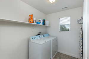 Laundry area with washing machine and clothes dryer and stone finish flooring